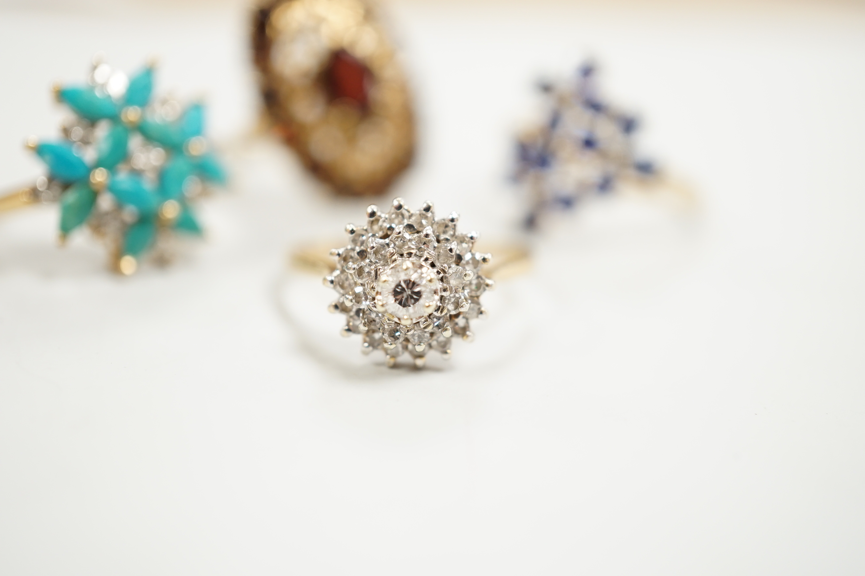 Four assorted modern 9ct gold and gem set dress rings including diamond cluster and garnet cluster, gross weight 13.6 grams.